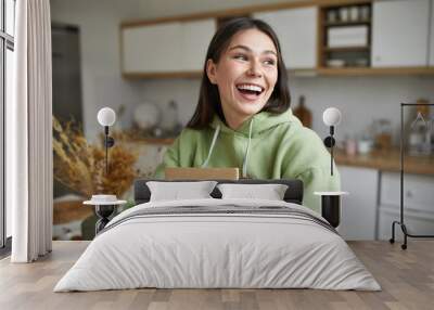 Shipment, delivery, moving and online shopping concept. Happy overjoyed young brunette woman posing indoors with small cardboard parcel in her hands with new books, clothing or food products Wall mural