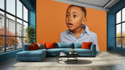 Startled astonished black dark skinned schoolboy posing in studio with mouth wide openend staring in front of him with fright, shock, can't believe his own eyes. Astonishment and surprise concept Wall mural