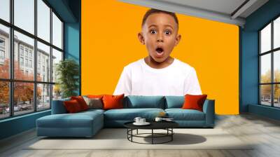 Surprise, excitement and fascination concept. Funny bug eyed African little boy opening his mouth widely, shocked with astonishing unexpected news, having amazed look, showing full disbelief Wall mural