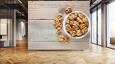 Walnuts in bowl on wooden table top view Wall mural