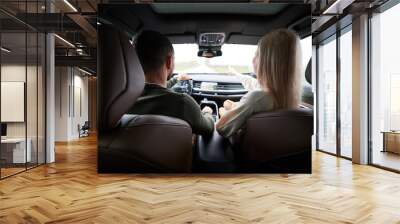 back view of man and woman traveling in car. beautiful young couple sitting on front passenger seats Wall mural