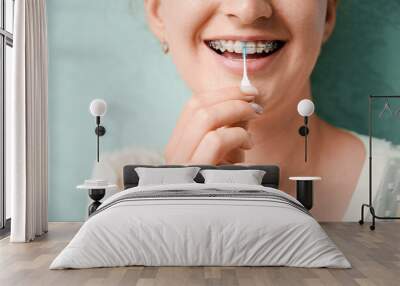 Close up of woman using elastic cleaning toothpick while brushing teeth with orthodontic brackets. Woman cleaning teeth with dental floss brush. Concept of dentistry, hygiene and dental care. Wall mural