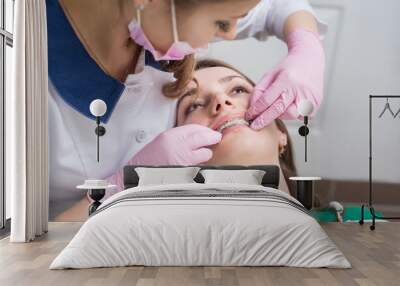 Female dentist checking up patient teeth with metal brackets at dental clinic office. Medicine, dentistry and health care concept. Dental equipment Wall mural