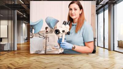 Portrait woman gynecologist working in gynecological cabinet with modern equipment. Doctor in blue shirt using colposcope in clinic. Concept if gynecology, healthcare and medical workers. Wall mural