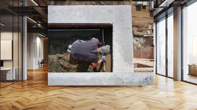 Top view of bricklayer in protective gloves working with sand and doing walls on fresh air. Concept of process building walls and modern house with good weather and modern equipments. Wall mural