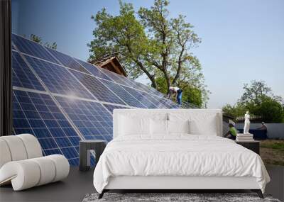 Two technicians installing solar panel photo voltaic system installation on steel platform on bright sunny summer day under blue sky. Renewable ecological green energy production concept. Wall mural