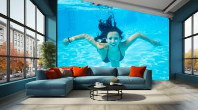 Underwater portrait of smiling female wearing in a black bathing suit in swimming pool, beautiful turquoise water. Close-up Wall mural