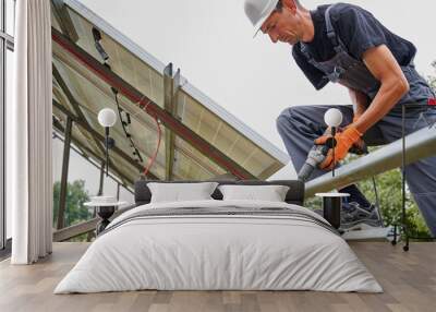 Worker fixing metal beams with electric drill for solar panels. Concept of renewable and ecological energy. Modern technology and innovation. Wall mural