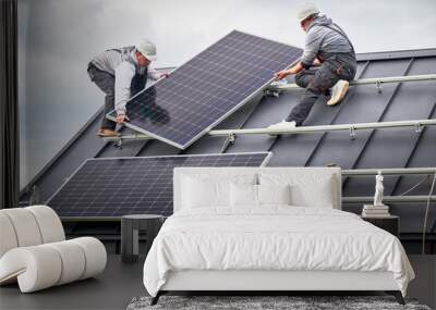 Workers building solar panel system on roof of house. Men technicians in helmets carrying photovoltaic solar module outdoors. Concept of alternative and renewable energy. Wall mural