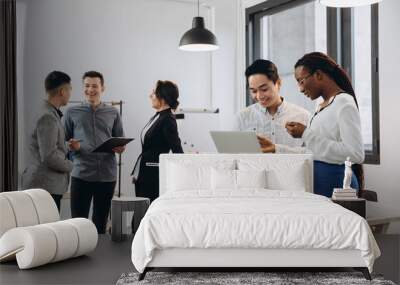 African businesswoman and Asian businessman using a laptop with interracial group of business men & women team Wall mural