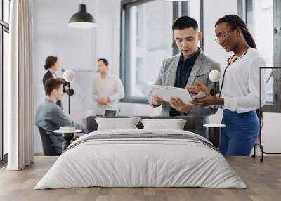 African businesswoman and Asian businessman using a tablet with interracial group of business men & women team Wall mural