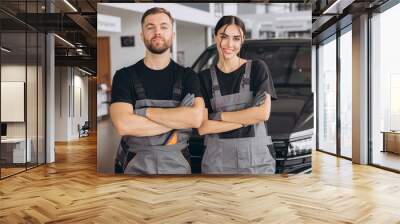 Auto car repair service center. Two happy mechanics - man and woman standing by the car Wall mural