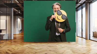 Business middle-aged bearded man in khaki suit holding emoji with glasses on a green background Wall mural