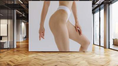 Close up view. Crop image of woman with slim body and perfect stomach in underwear posing in the white studio background. Wall mural