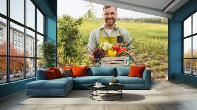 Happy farmer man holding basket with fresh vegetables in garden, gardening concept Wall mural