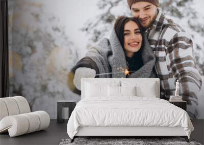 Happy romantic couple in love holding sparklers in snowy winter forest Wall mural