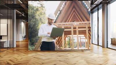 Man builder. Foreman with laptop. Contractor for construction company. Architect in unfinished building. Builder in wooden house under construction. Man engineer from construction team Wall mural