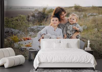 Mother Enjoying a Lovely Outdoor Picnic with Her Two Happy Children in a Field Wall mural