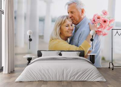 Senior couple with bouquet pink flowers on the background of the old architecture Wall mural