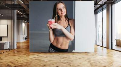 Sports girl after exercise relaxes in a bright room and cocktail drinks Wall mural