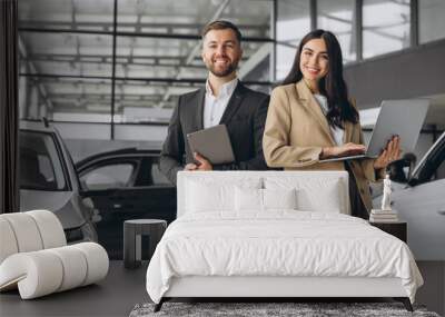 Super sales team in dealership, two consultants or managers in elegant suits with laptop and tablet in arms in car dealership Wall mural