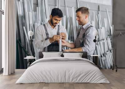 Two international male workers in uniform discuss the work process at a metal-plastic window factory Wall mural