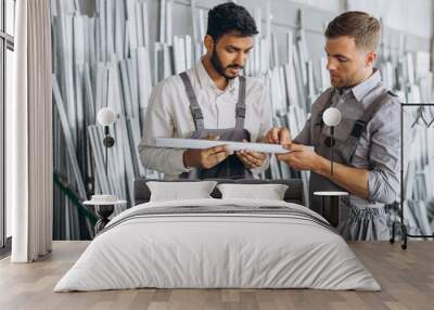 Two international male workers in uniform discuss the work process at a metal-plastic window factory Wall mural