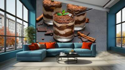 Classic tiramisu dessert in a glass cup and pieces of chocolate on dark concrete background Wall mural