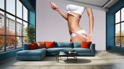 Slim tanned woman's body over gray background Wall mural