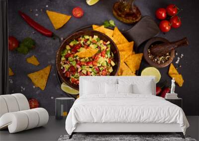 traditional salsa dip snack in wooden bowl and corn nacho chips on a table with ingredients Wall mural