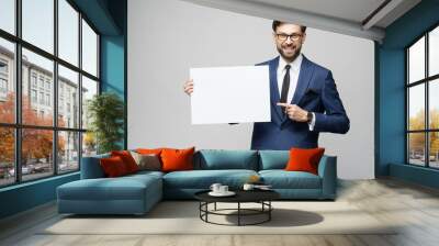 Young businessman holding blank signs over grey background Wall mural