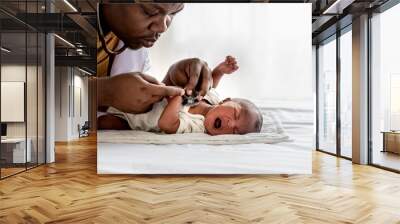 African doctor using a stethoscope, checking the respiratory system and heartbeat Of a 12-day-old baby black skin newborn, which laying and crying on the bed, to baby black skin and  health concept Wall mural