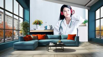 Asian female doctor Relaxing by listening to music from headphones While resting from the treatment of patients at the clinic with white background, to people and health care concept. Wall mural