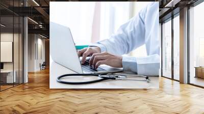 The doctor is using a notebook computer, In search of information And write a report about the patien's condition, on the desk at workplace with white background, to health care and insurance concept. Wall mural