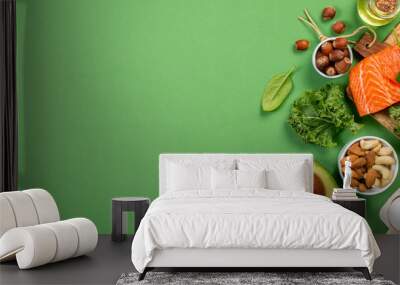 Keto diet concept - salmon, avocado, eggs, nuts and seeds, bright green background, top view Wall mural