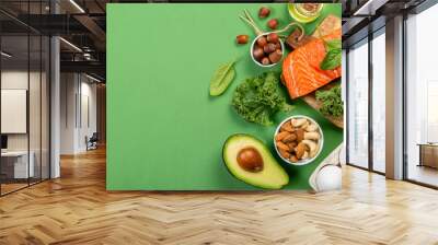 Keto diet concept - salmon, avocado, eggs, nuts and seeds, bright green background, top view Wall mural