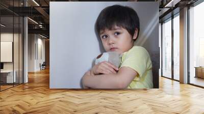 Dramatic portrait of little boy sitting on stair and cuddling teddy bear with scared face,Unhappy Child sitting alone and looking out with worrying face,Toddler boy on corner punishment sitting. Wall mural