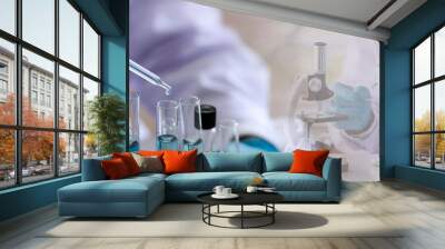 Laboratory concept; Scientist uses a dropper to transfer chemical reagent to test tube. He observes the chemical reaction with a blurred background of research in the laboratory Wall mural