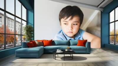 Portrait kid looking out deep in thought, Lonely Child sitting on stairs carpet with thinking face, Childhood and family concept, Selective focus Emotional child portrait Wall mural