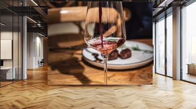 A hand is pouring wine into red wine glass  Wall mural