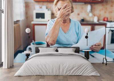 Elderly woman looking at her utility bills Wall mural