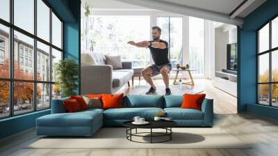 Handsome man working out at home Wall mural