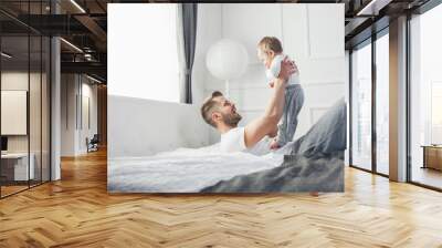 Happy father with his son playing at home on the bed Wall mural