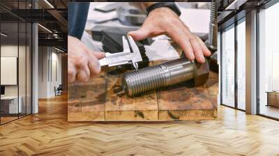 The worker measures the thread pitch on the bolt with a vernier caliper, after turning. Quality control department. Wall mural