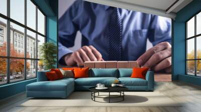 Businessman holding wooden cube on a wooden table. Wall mural