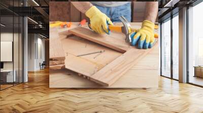 Carpenter with hammer hitting nail on wooden plank. Wall mural