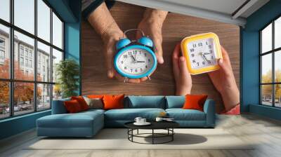 Hands of elderly female and young girl holding clock. Wall mural