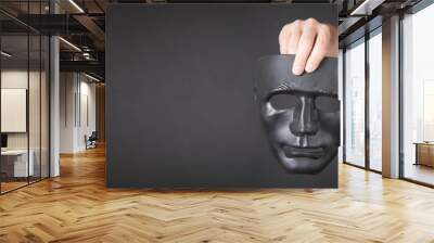 Man holding black mask. Fake, anonymous Wall mural