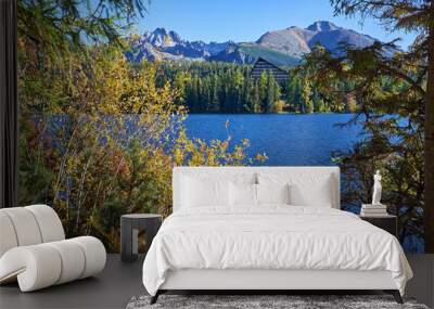 Vivid blue water Strsbke Pleso lake framed by beautiful autumn foliage with the Hight Tatras mountains in the background in Slovakia Wall mural