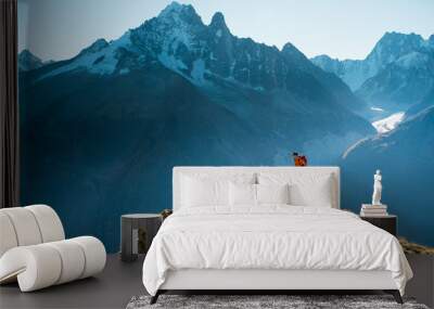 A hiker on top of a rocky summit in the mountains of the Alps Wall mural